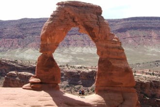 Guests taking pictures with a breathtaking arch on Best of Moab Mountain Bike tour with Escape Adventures