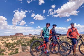 Guests posing with amazing views on Canyonlands, Arches and Moab multi sport mountain bike tour with Escape Adventures